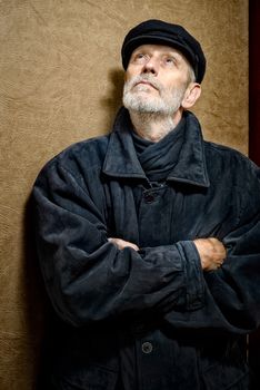 Portrait of a mature man with a white beard and a cap on the head. He could be a sailor, a worker, a docker, or even a gangster or a thug. He is looking up.