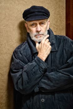 Portrait of a mature man with a white beard and a cap on the head. He could be a sailor, a worker, a docker, or even a gangster or a thug. He has a penetrating gaze.