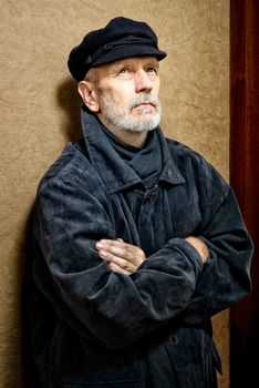 Portrait of a mature man with a white beard and a cap on the head. He could be a sailor, a worker, a docker, or even a gangster or a thug. He has a penetrating gaze.