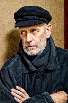 Portrait of a mature man with a white beard and a cap on the head. He could be a sailor, a worker, a docker, or even a gangster or a thug. He has a penetrating gaze.