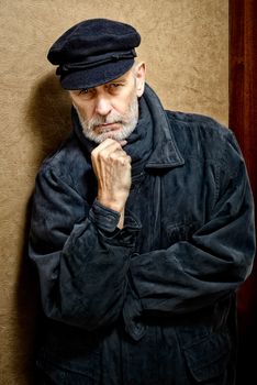 Portrait of a mature man with a white beard and a cap on the head. He could be a sailor, a worker, a docker, or even a gangster or a thug. He has a penetrating gaze.