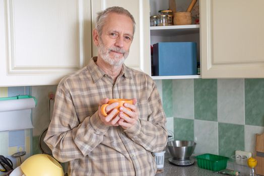 Mature man drinking his coffee in an orange cup, at morning in kitchen