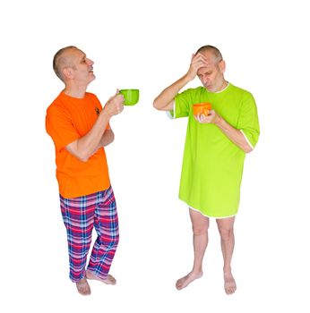 A couple of twin men drinking coffee or herbal tea after waking up. One is in green nightdress, holding an orange cup, the other is in pajamas with an orange T-shirt, and is holding a green cup