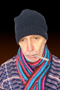 Sick man with the flu and temperature, wearing a cap and a woolen scarf, on dark background