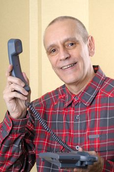 A senior man giving the phone handset to somebody else - There is a call for you!