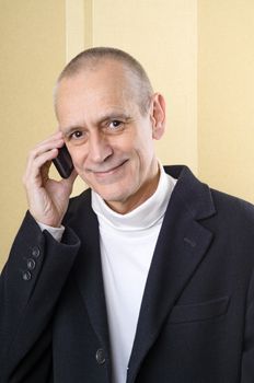 Handsome businessman with a black coat, smiling and speaking on mobile phone