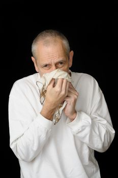 A sick man with cold holding an handkerchief in hands and blowing his nose