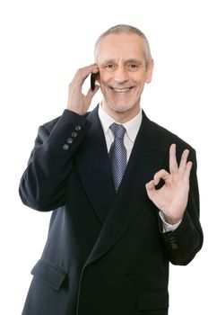 An amiable businessman smiling on mobile phone and showing the okay sign with the hand