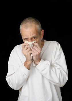 A sick man with cold holding an handkerchief in hands and blowing his nose