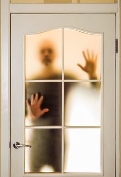 Silhouette of an unknown man in black  seen behind a closed glass door, like a ghost or an alien