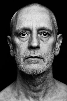 Dramatic black and white portrait of an adult man with sad expression on black background