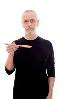 Adult man in black holds a spoon in each and looks serious