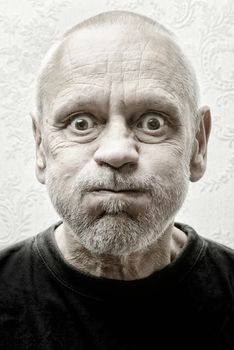 Black and white portrait of a funny and crazy caucasian man making faces with eyes round like balls and puffy cheeks