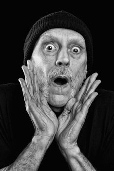 Dramatic black and white photo of a strong man with a beard with a woolen cap on the head, shouting out loud with the hands in a megaphone gesture