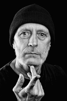 Dramatic black and white photo of a strong man with beard with a woolen cap on the head, pointing finger, with an agressive look.