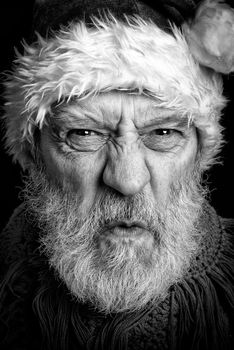 Black and white portrait of an adult man with white beard disguised in  angry Santa Claus for the Christmas Holiday