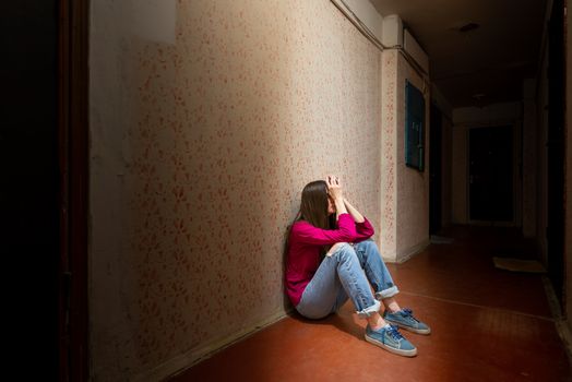 A sad and desperate woman sits in a dark corridor illuminated by a gloomy light. Her pain and her many problems pushed her into complete isolation. His sadness is only equalled by his loneliness.