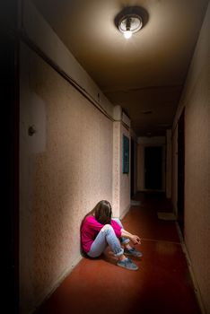 A sad and desperate woman sits in a dark corridor illuminated by a gloomy light. Her pain and her many problems pushed her into complete isolation. His sadness is only equalled by his loneliness.