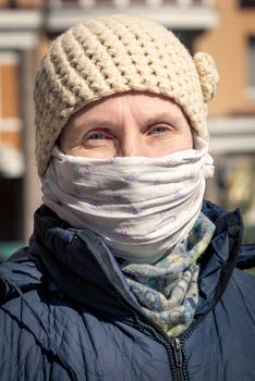 A poor elderly woman wears a homemade mask to protect herself from viruses such as coronavirus, also known as covid-19, or SARS and MERS. She's in an urban environment