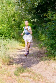 A happy senior woman is running in the forest during a warm summer day