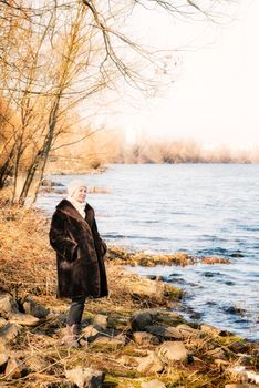 A mature woman wearing a warm fur coat and a woolen cap stays close to the Dnieper river in Kiev, Ukraine, during winter