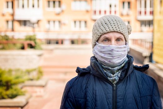 A poor elderly woman wears a homemade mask to protect herself from viruses such as coronavirus, also known as covid-19, or SARS and MERS. She's in an urban environment