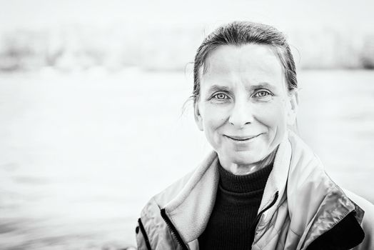 A warm portrait of a nice smiling senior woman close to the river