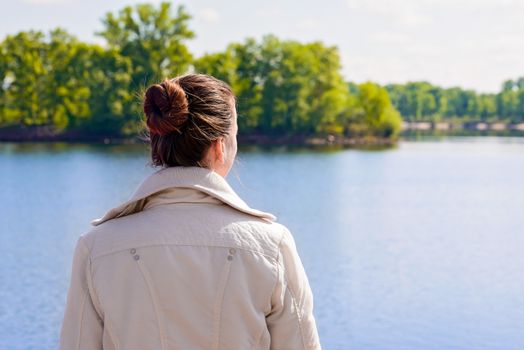 A woman with a chignon looking at the river during a nice sunny spring morning