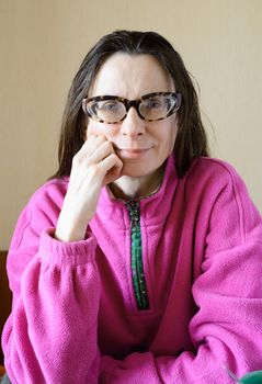 A smiling mature woman with glasses wearing a pink pull-over at morning after breakfast