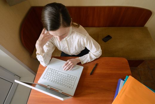 An elegant business woman is using a laptop computer. She is satisfied of her work.