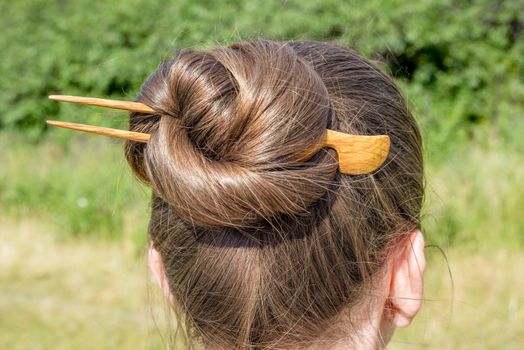 Detail of a chignon with a wooden hairpin to keep the hair attached together