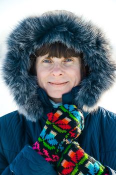 A soft portrait of a fifty years old woman. The image is shot on an iced lake, giving a nice light reflection from the ground