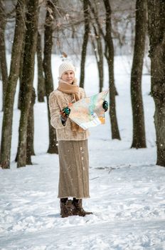 A woman lost in the forest in winter, is seeking her way to home on the map