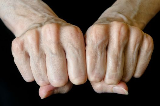 Senior woman showing fists on black background