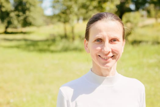 A warm portrait of a nice smiling senior woman in the park under the warm summer sun