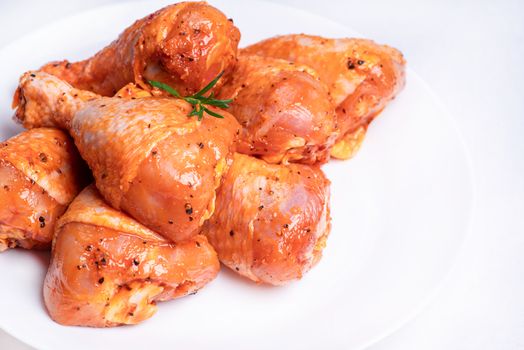 Raw marinated chicken legs for grill and bbq.Chicken legs in a red marinade on a white plate. Top view. Chicken meat close-up.. Dietary meat. Cooking.Isolate.