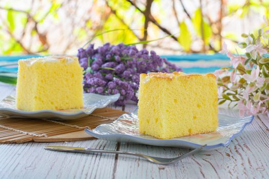 Piece of vanilla chiffon coconut cake on square plate on wooden table. Delicious small bakery for coffee and tea times.