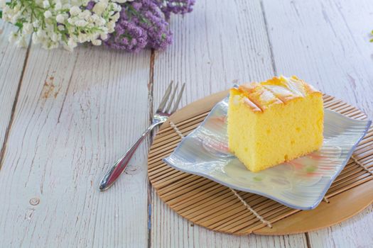 Piece of vanilla chiffon coconut cake on square plate on wooden table. Delicious small bakery for coffee and tea times.