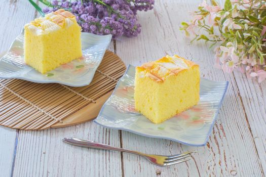 Piece of vanilla chiffon coconut cake on square plate on wooden table. Delicious small bakery for coffee and tea times.