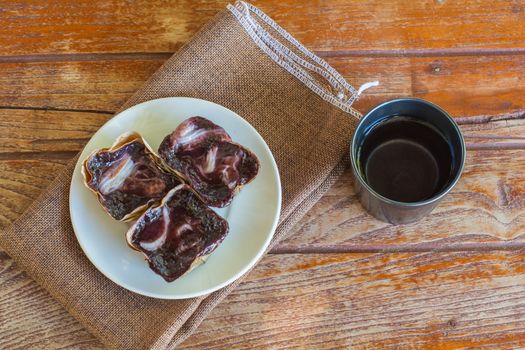 Black sticky rice cake Nian Gao in dried banana leave cup on white plate and wooden table. Traditional snack in Chinese new year.