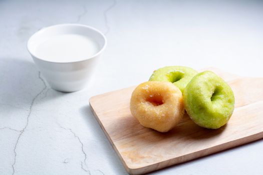 Vanilla and pandan doughnut on wooden chopping board with cup of hot milk. Breakfast concept.