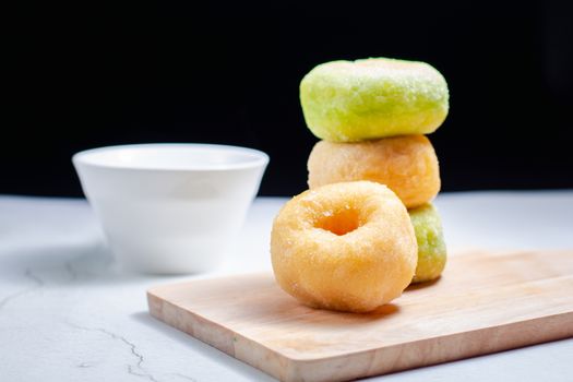 Vanilla and pandan doughnut on wooden chopping board with cup of hot milk. Breakfast concept.