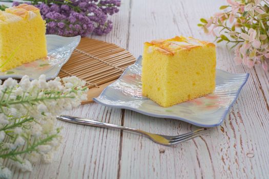 Piece of vanilla chiffon coconut cake on square plate on wooden table. Delicious small bakery for coffee and tea times.