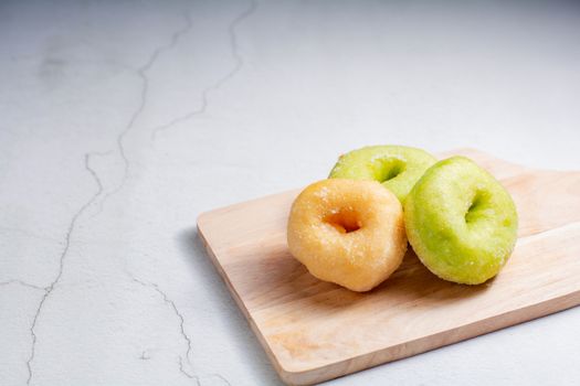 Vanilla and pandan doughnut on wooden chopping board. Breakfast concept.