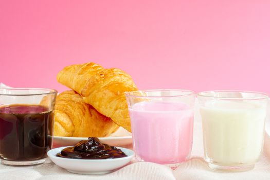 croissants served with glass of Fresh milk, coffee on pink background. Breakfast concept.