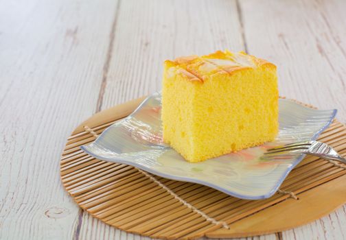 Piece of vanilla chiffon coconut cake on square plate on wooden table. Delicious small bakery for coffee and tea times.