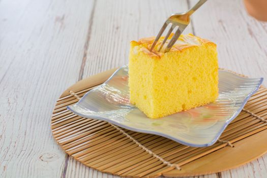 Piece of vanilla chiffon coconut cake on square plate on wooden table. Delicious small bakery for coffee and tea times.