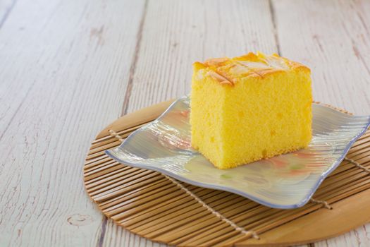 Piece of vanilla chiffon coconut cake on square plate on wooden table. Delicious small bakery for coffee and tea times. Copyspace for your text.