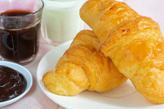 croissants served with glass of Fresh milk, coffee on pink background. Breakfast concept.