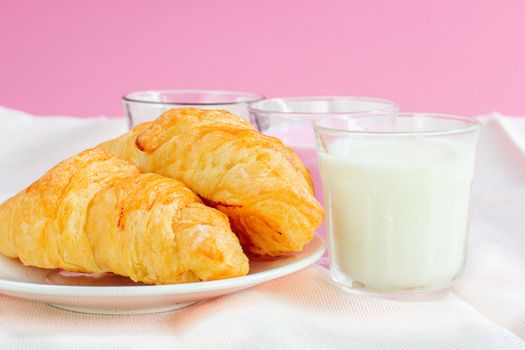 croissants served with glass of Fresh milk, coffee on pink background. Breakfast concept.